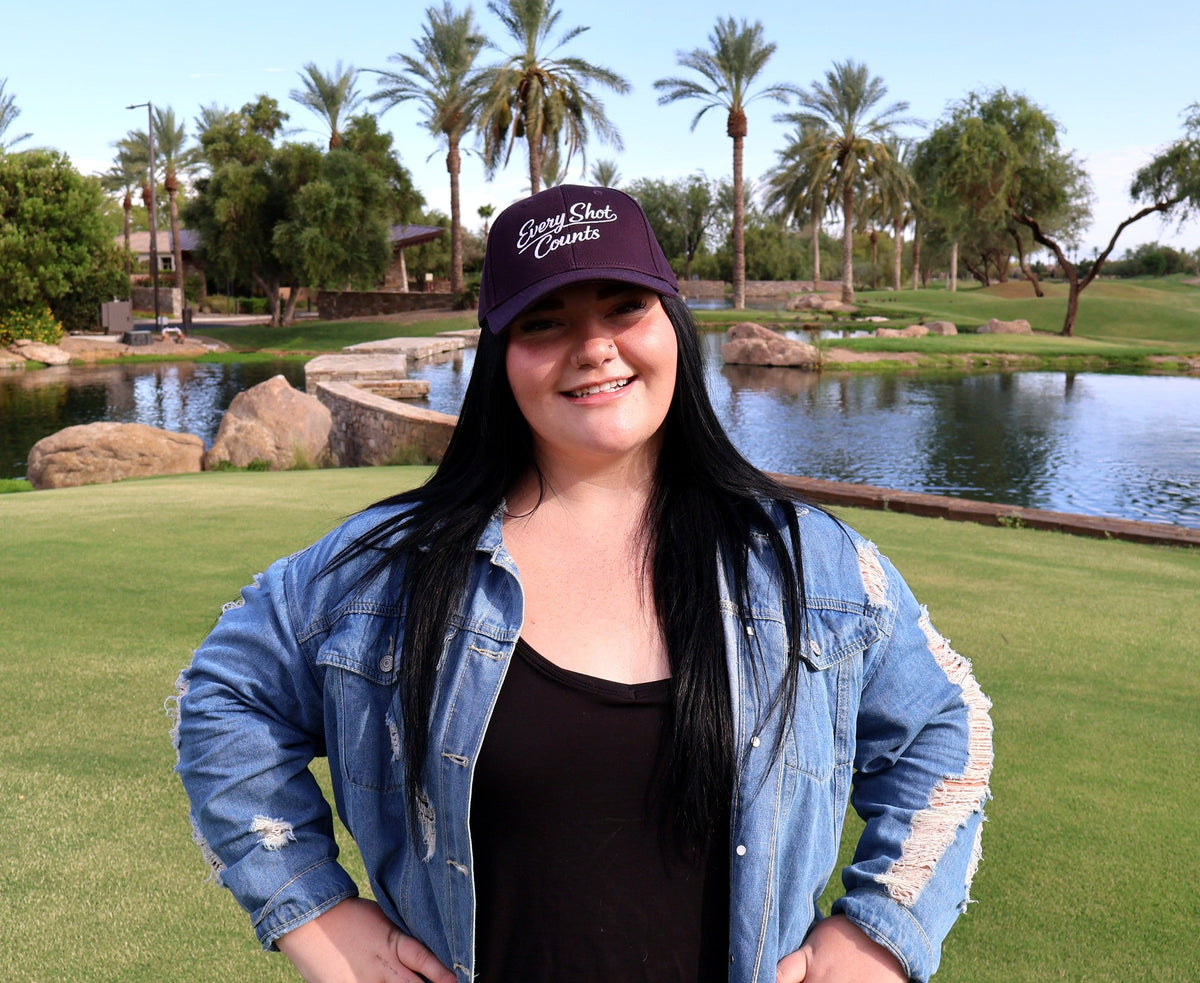 Woman wearing the navy Every Shot Counts embroidered golf hat on the course