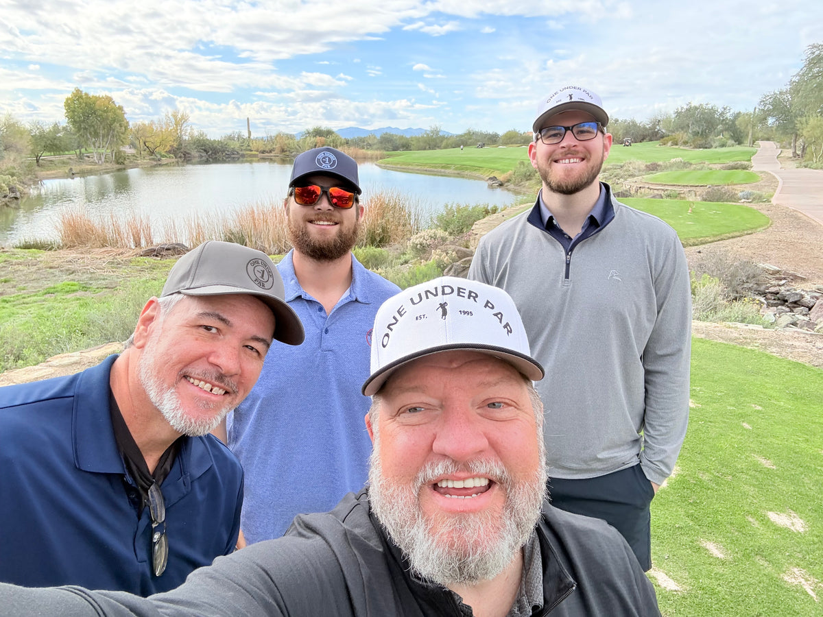 Two golfers wearing One Under Par hats together at Quintero Golf Club